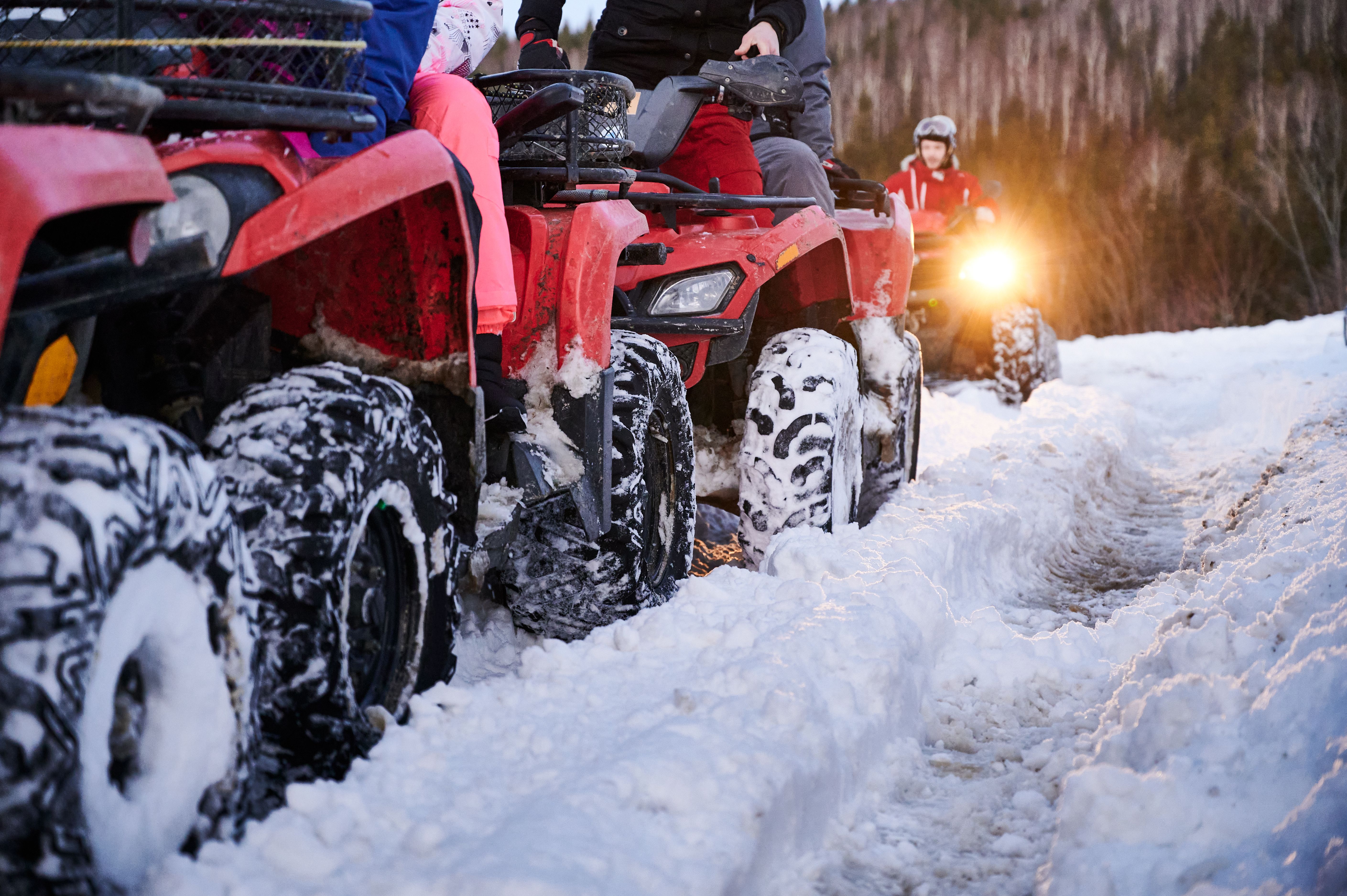 Groupe de personnes conduisant des quad VTT sur un chemin enneigé